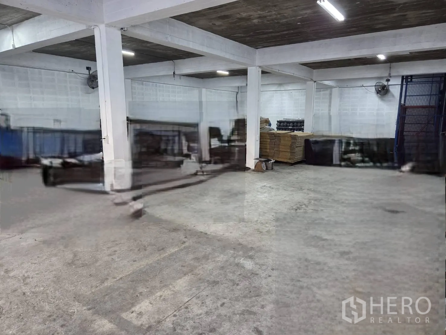 โกดัง for rent in Ratchathewi, Bangkok - พื้นที่ชั้นล่างภายในโกดัง พื้นคอนกรีต เสาโครงสร้าง พัดลมติดผนัง และไฟแสงสว่าง.