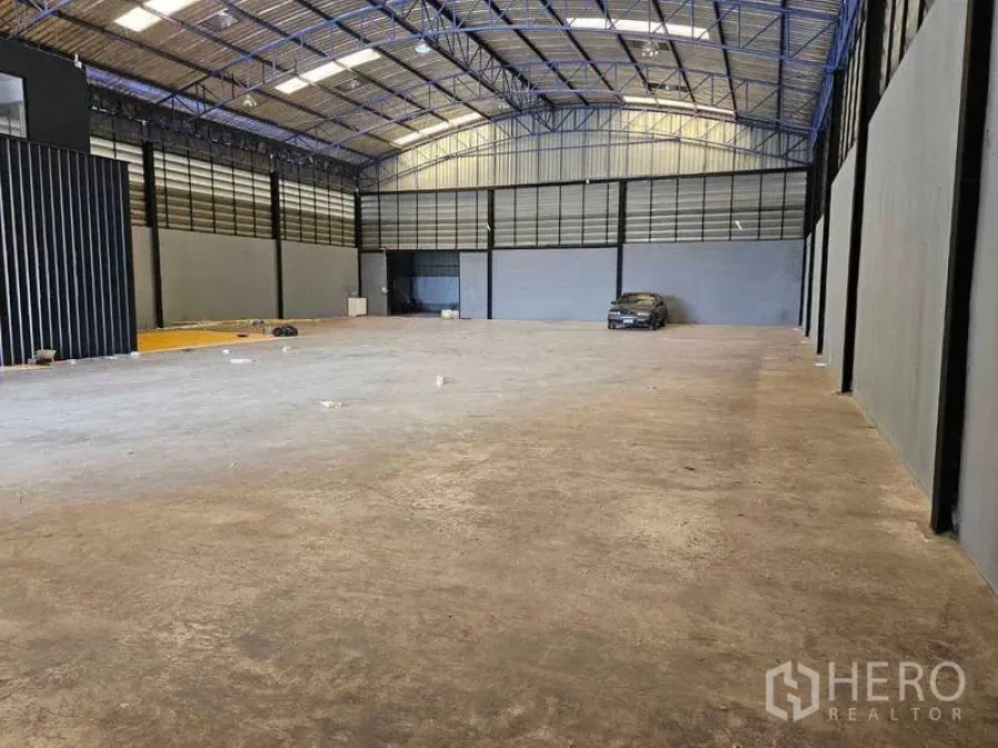 Warehouse for rent or sale in Khlong Toei, Bangkok - Spacious high-ceiling warehouse with steel truss roof and polished concrete floor, car parked at the far end in Khlong Toei, Bangkok.
