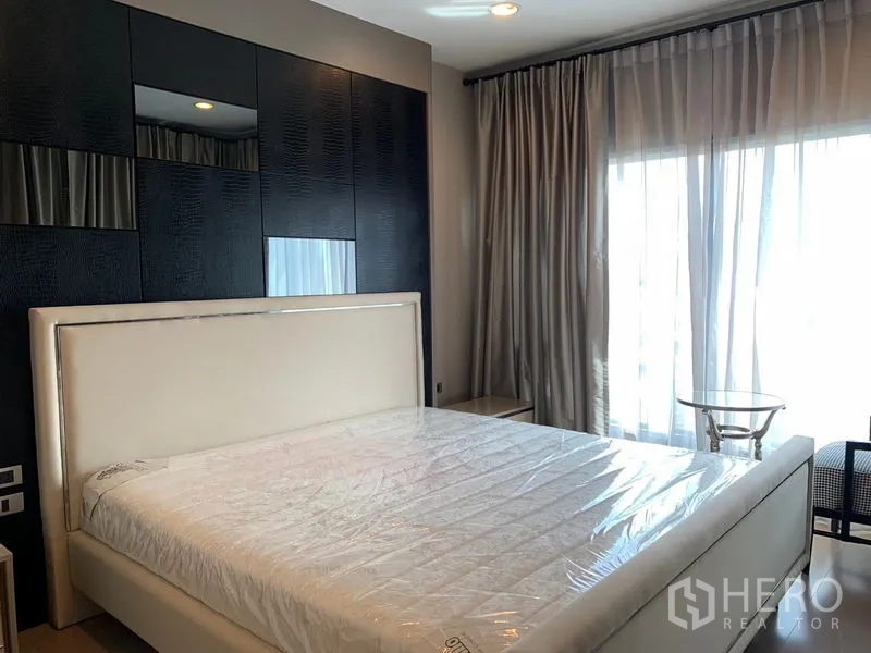 公寓 出租在Khlong Toei, Bangkok - 卧室配软包床头、深色特色墙、纱帘与阳台门。