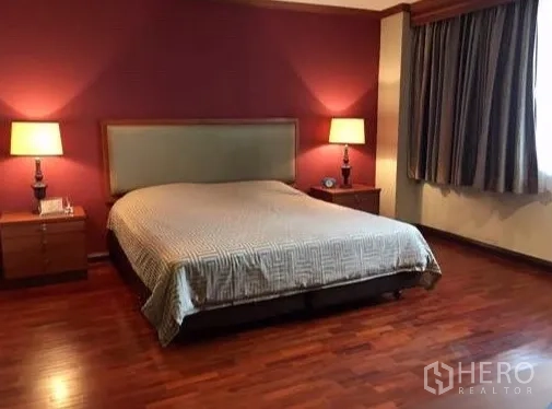 Condominium for rent or sale in Watthana, Bangkok - Spacious bedroom with king bed, twin lamps and wood flooring.
