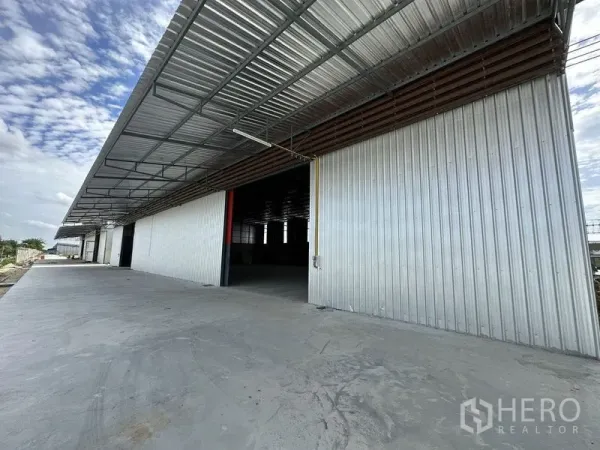 Warehouse for rent in Lam Luk Ka, Pathum Thani - Industrial frontage with oversized sliding door and spacious concrete driveway for easy vehicle access.