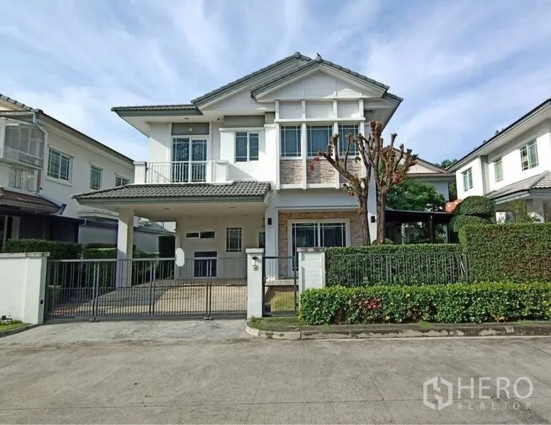 บ้าน ขายในPrawet, Bangkok - ด้านหน้าบ้านเดี่ยวสองชั้นสมัยใหม่ พร้อมที่จอดรถมีประตูและรั้วพุ่มไม้