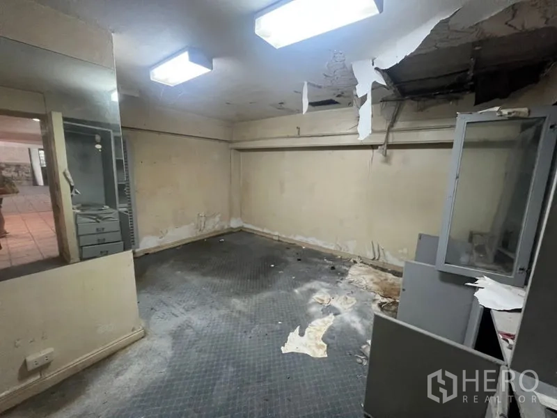 Retail Space for rent in Watthana, Bangkok - Rear room with peeling ceiling and fluorescent lights, fit-out required.