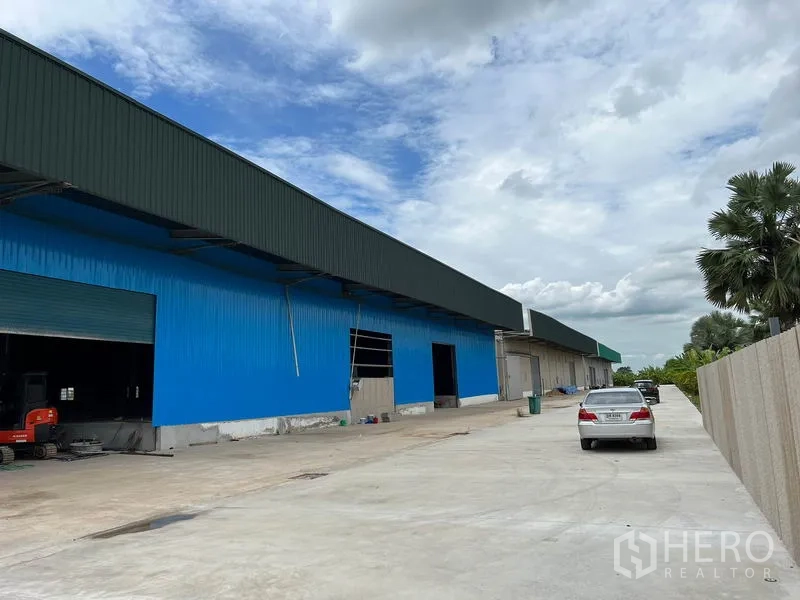 货栈 出租在Lat Krabang, Bangkok - 沿仓库的长车道与停车区，可见多个大型卷帘门。