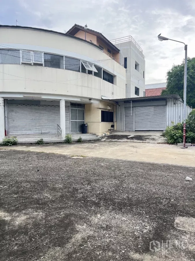 货栈 出租在Huai Khwang, Bangkok - 辉煌区仓库外立面，曲线建筑，卷闸门与宽阔装卸区。