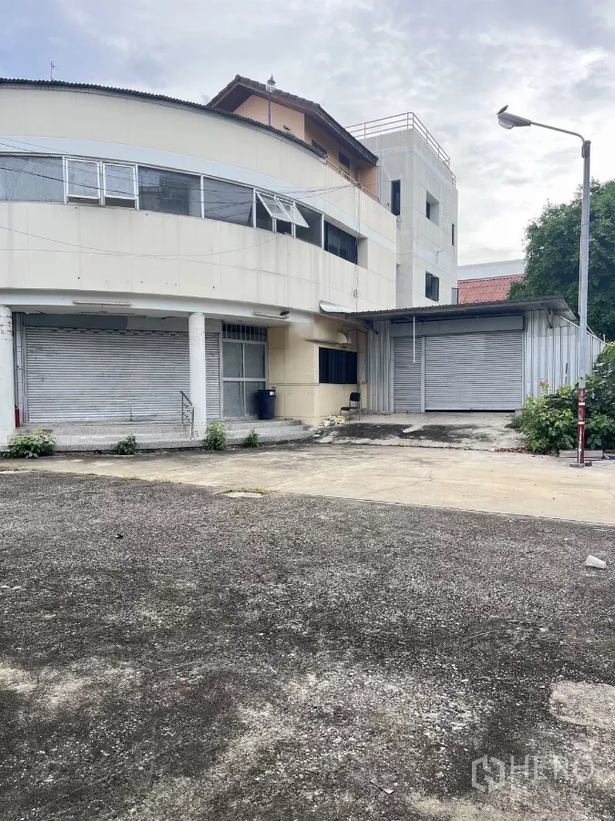 货栈 出租在Huai Khwang, Bangkok - 辉煌区仓库外立面，曲线建筑，卷闸门与宽阔装卸区。