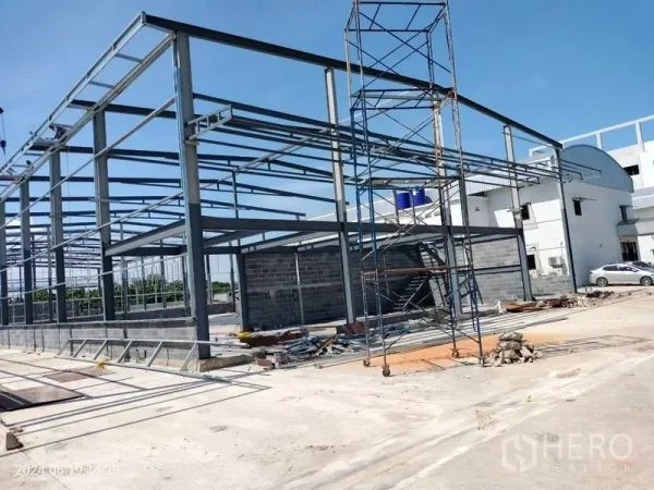 货栈 出租在Samut Prakan - 仓库侧视图，钢结构配脚手架与材料，铺装装卸区清晰可见。
