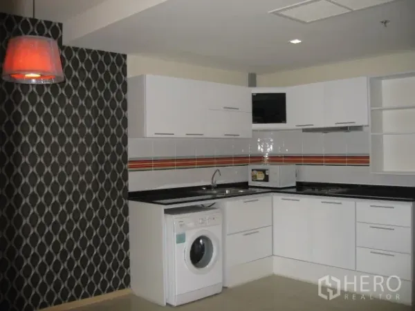 Condominium for rent in Khlong Toei, Bangkok - Modern U-shaped kitchen with white cabinetry, tile backsplash, washing machine, and pendant light.
