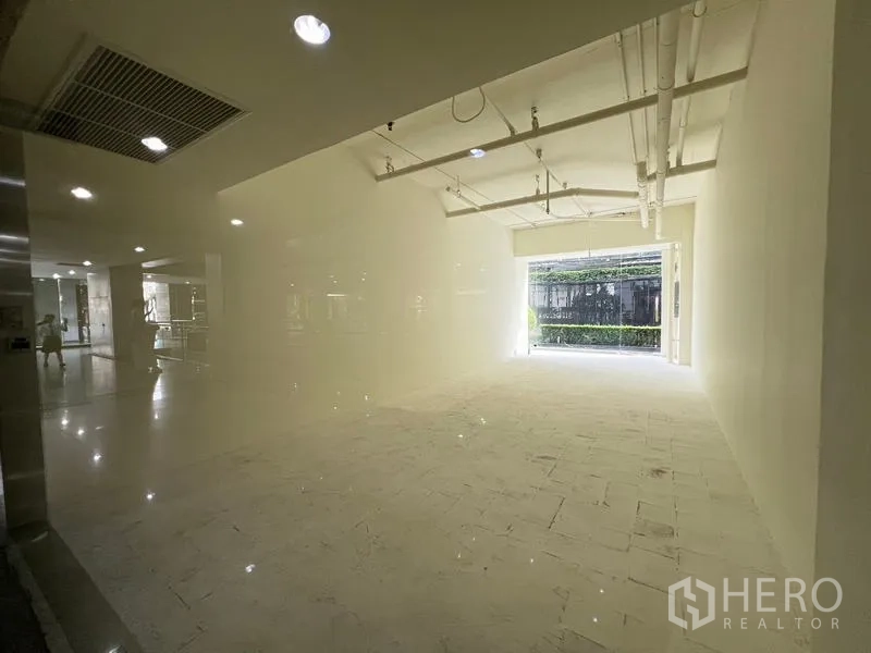 Retail Space for rent in Watthana, Bangkok - Bright 39 sqm retail unit with high ceiling and white-box finish, natural light at the entrance.