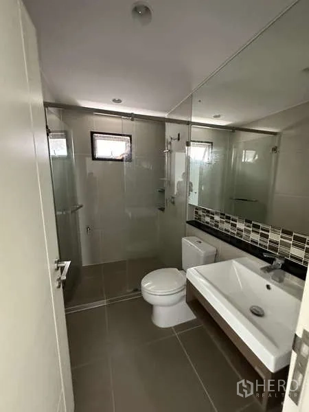 Detached House for sale in Lam Luk Ka, Pathum Thani - Bathroom with glass shower enclosure and oversized mirror.