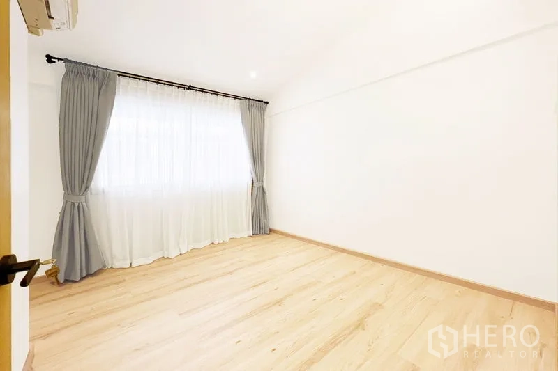 Townhouse for rent in Khlong Toei, Bangkok - Sunlit bedroom with wood flooring, full curtains and wall-mounted air conditioner.