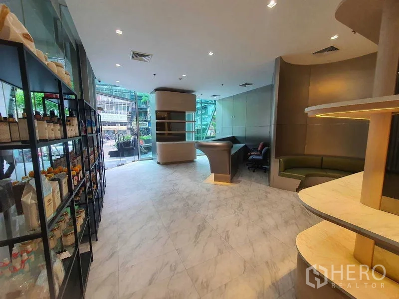 Retail Space for rent in Bang Rak, Bangkok - Modern retail unit with floor-to-ceiling glass frontage, marble-look flooring, display shelving and a curved counter.