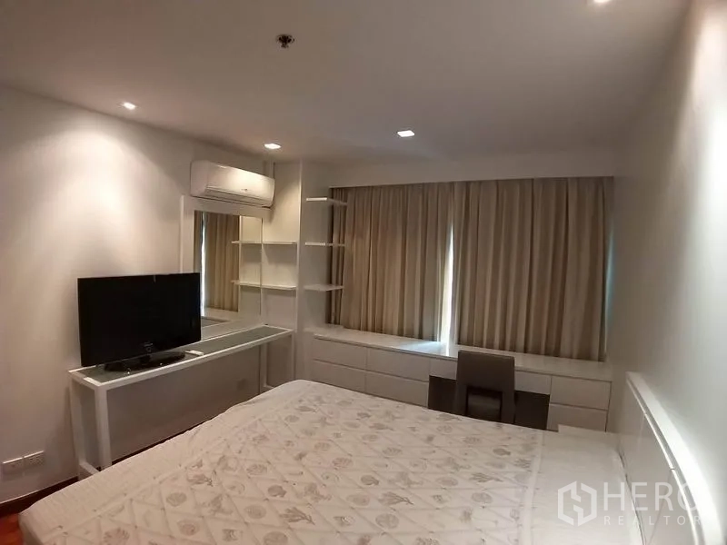 Condominium for rent or sale in Pathum Wan, Bangkok - Cozy bedroom with large bed, curtains, built-in shelves and study desk.