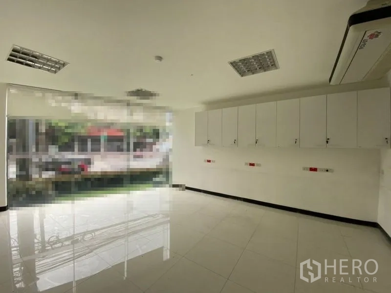 Retail Space for rent - Bright retail unit interior with floor‑to‑ceiling glass, wall cabinets and tiled floors in Watthana, Bangkok.