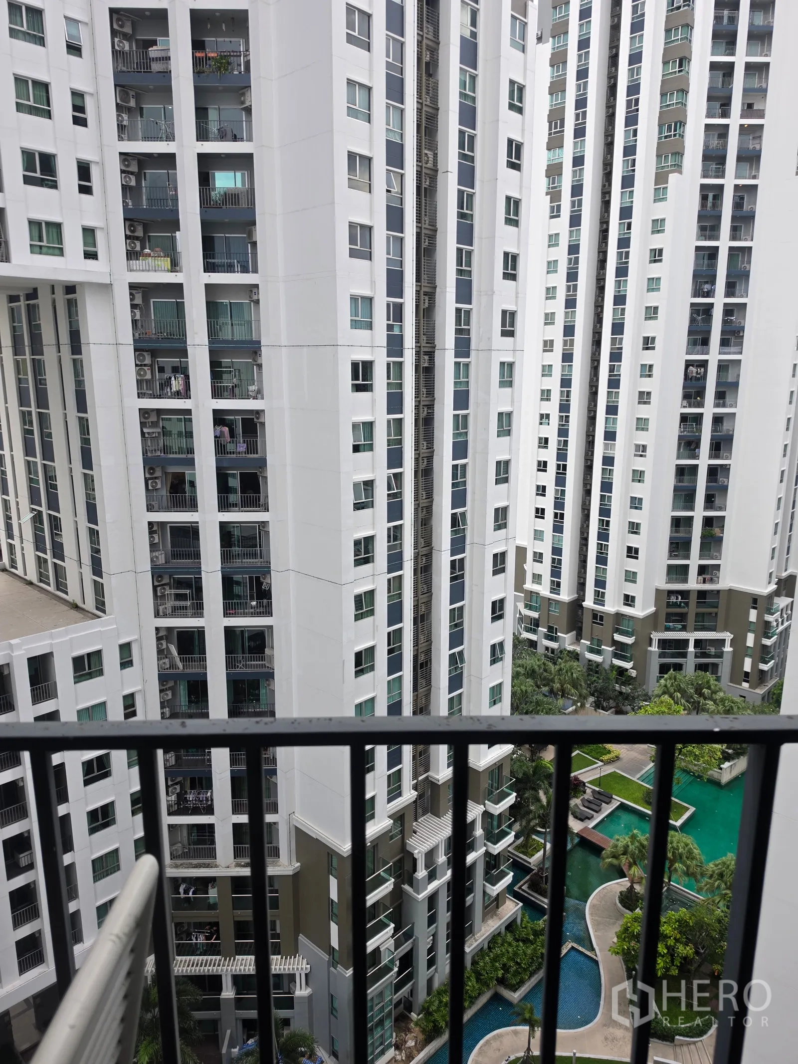 Condominium for rent in Huai Khwang, Bangkok - Balcony view of high-rise towers and a landscaped pool courtyard.