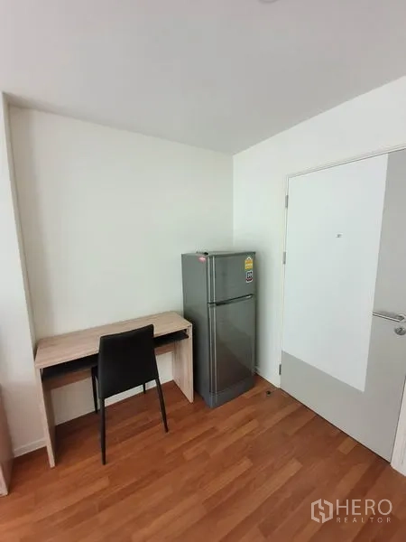 公寓 出售在Chatuchak, Bangkok - 紧凑工作角，木质书桌、黑色椅子与银色冰箱在入户旁。