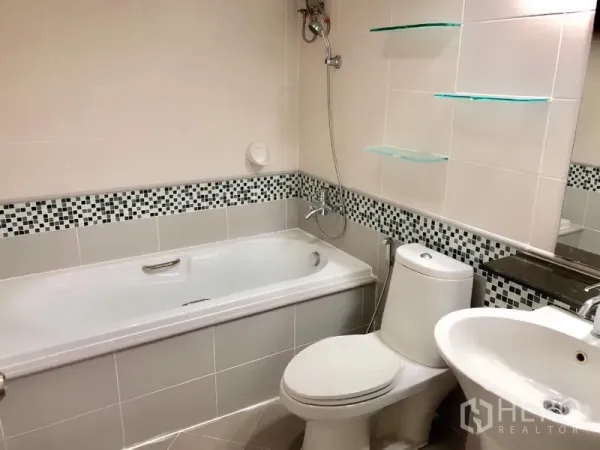 Condominium for rent or sale in Khlong Toei, Bangkok - Tiled bathroom featuring a bathtub with shower, toilet, and basin with mosaic accent border.