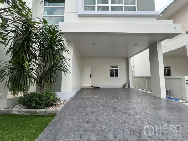 Detached House for rent in Saphan Sung, Bangkok - Covered carport and wide driveway beside a white exterior and small garden.
