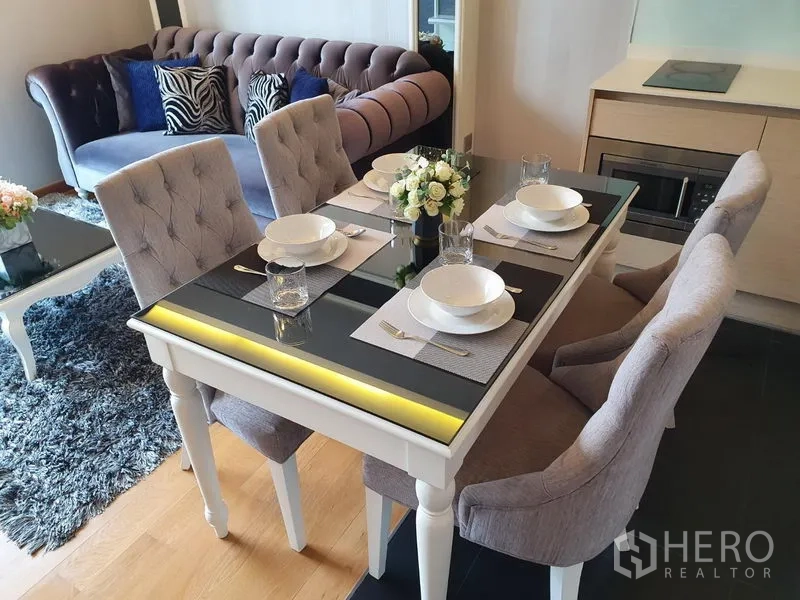 Condominium for rent in Watthana, Bangkok - Elegant four-seat dining table with tufted chairs beside a plush sofa in a 1-bedroom Watthana condo.