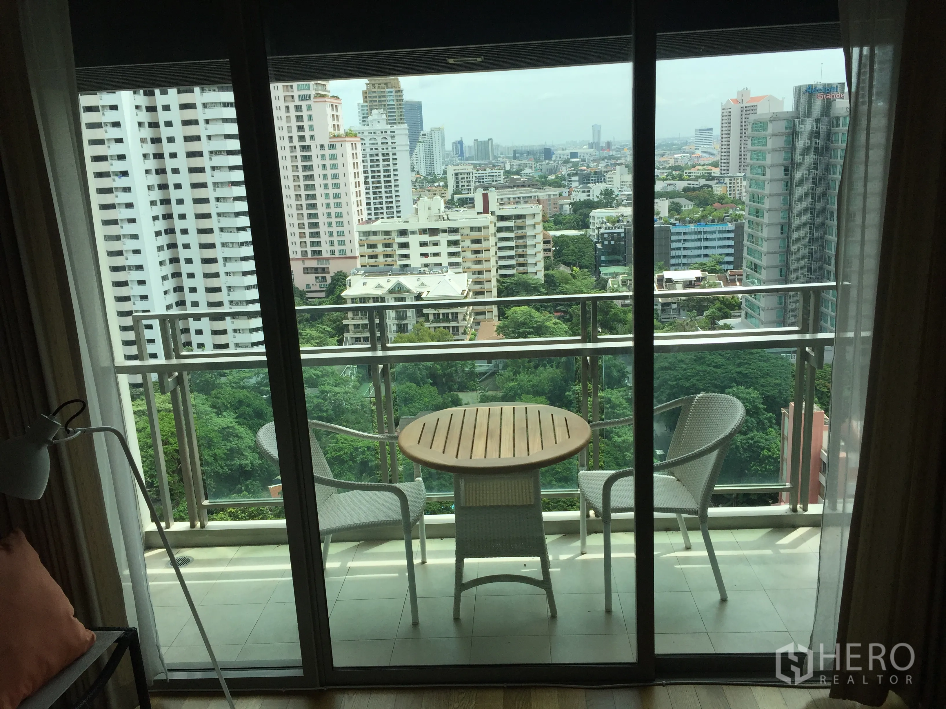 公寓 出租在Watthana, Bangkok - 高楼阳台，配户外桌椅，俯瞰绿地与天际线。