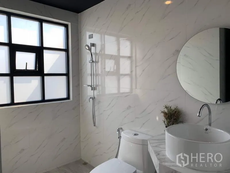 Townhouse for rent in Bang Kapi, Bangkok - Bright bathroom with marble-look tiles, round mirror, vanity and walk-in shower.