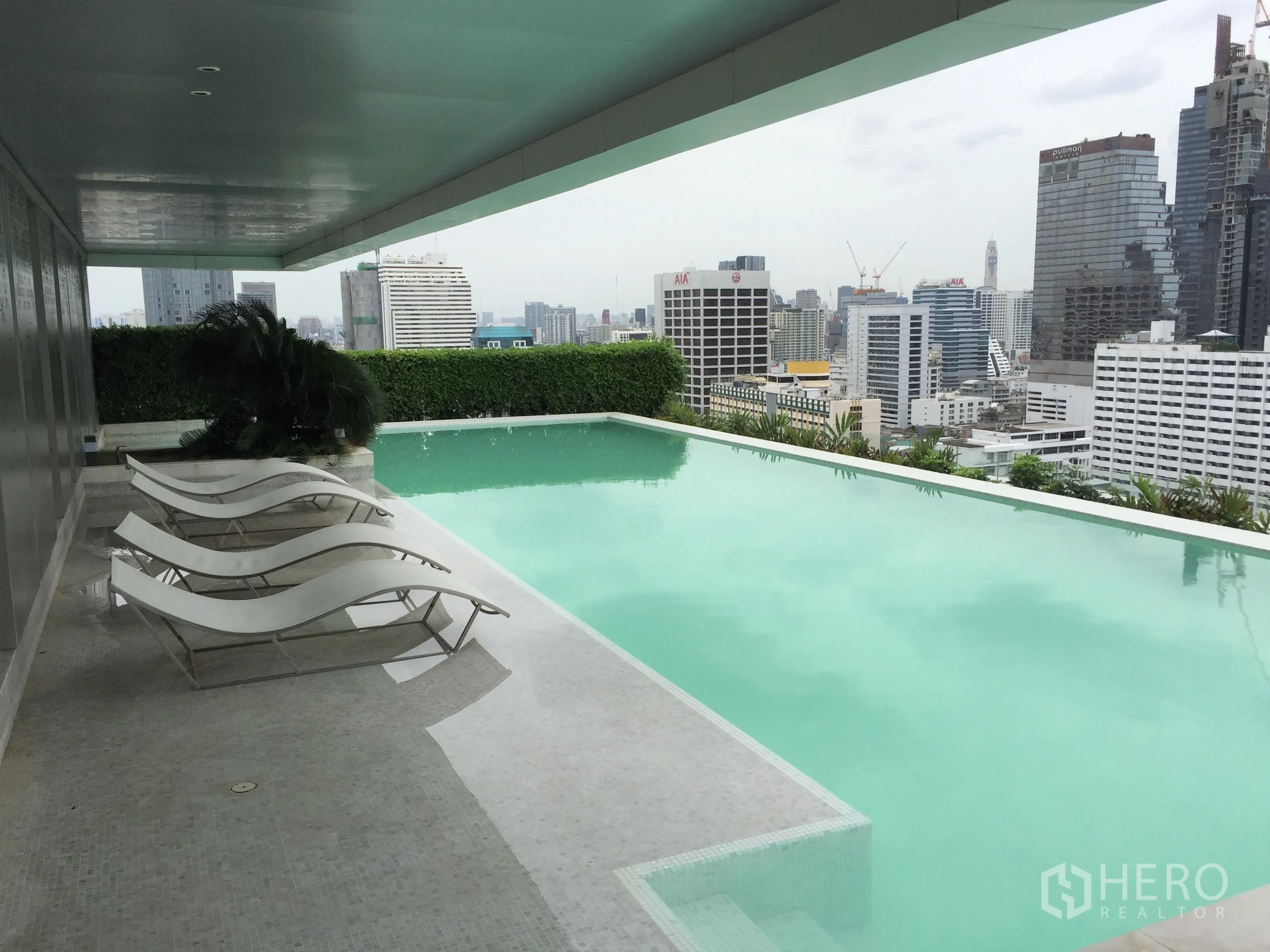 Condominium for rent in Bang Rak, Bangkok - Rooftop infinity-edge swimming pool with sun loungers and Bangkok skyline views.