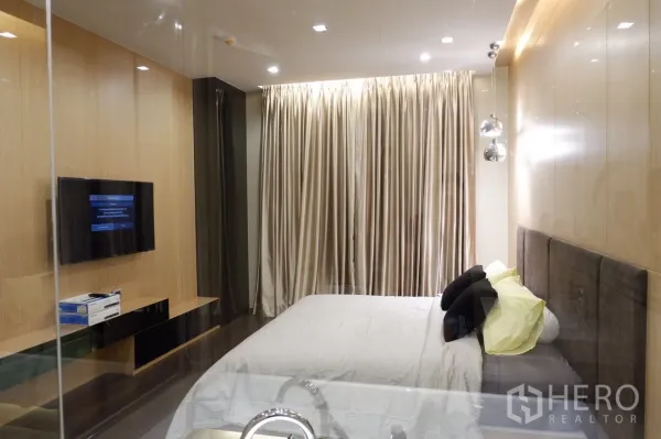 คอนโด ให้เช่าในWatthana, Bangkok - มุมมองห้องนอนพร้อมทีวีติดผนัง ผ้าม่านทึบยาว ตู้วางของบิวท์อิน และแสงไฟอบอุ่น