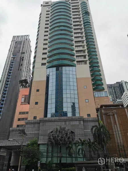 公寓 出租在Watthana, Bangkok - Las Colinas 公寓高层外观，绿色弧形阳台与玻璃立面。