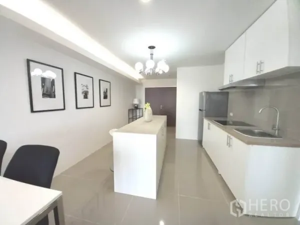 公寓 出租在Khlong Toei, Bangkok - 长形厨房，柜体充足，中岛操作台与装饰画，简洁清新。