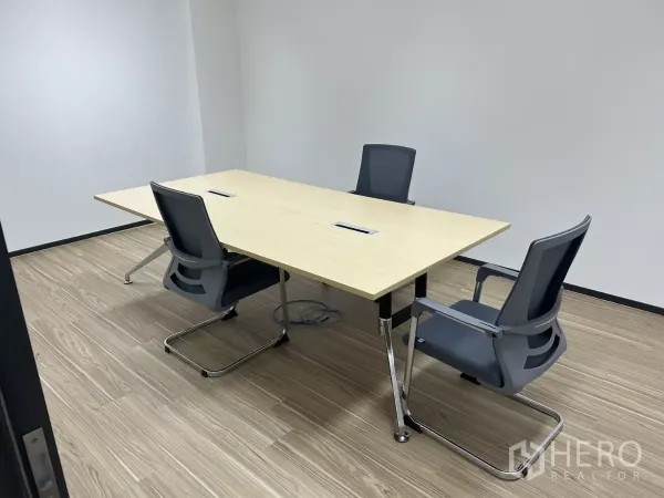 Office Space for rent - Compact meeting room with a rectangular table and three chairs on wood floors and clean white walls.