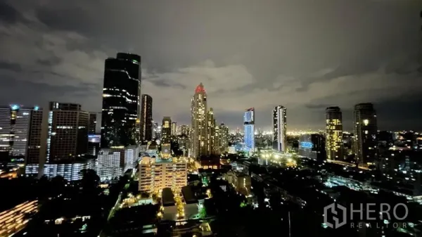 Condominium for sale in Sathon, Bangkok - High-floor night view of the Sathorn CBD skyline with illuminated skyscrapers and city lights.