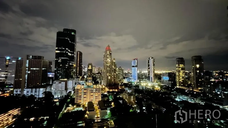 Condominium for sale in Sathon, Bangkok - High-floor night view of the Sathorn CBD skyline with illuminated skyscrapers and city lights.