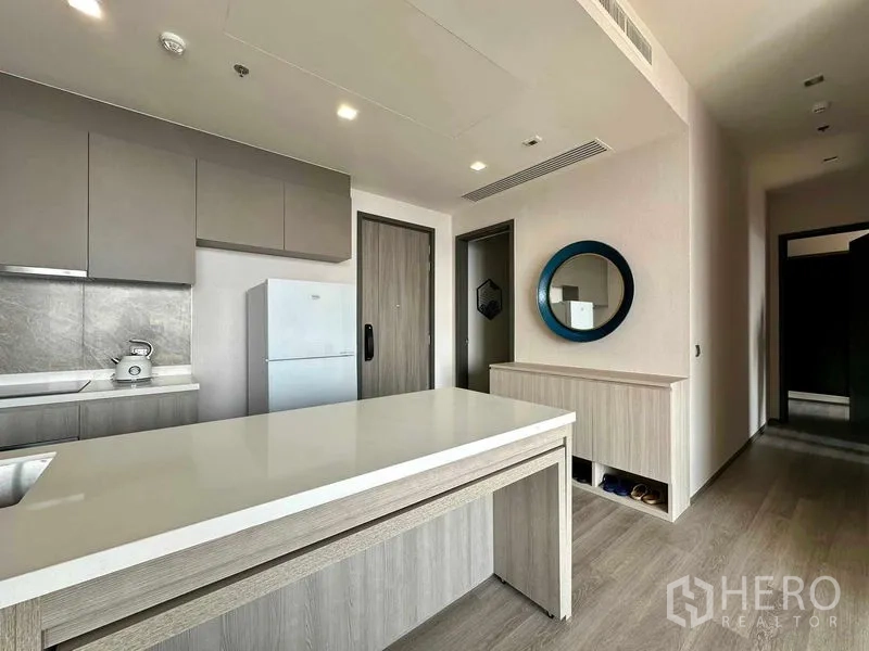 Condominium for rent in Bang Kho Laem, Bangkok - Sleek kitchen and entry hall featuring an island counter, gray cabinets and a round wall mirror.