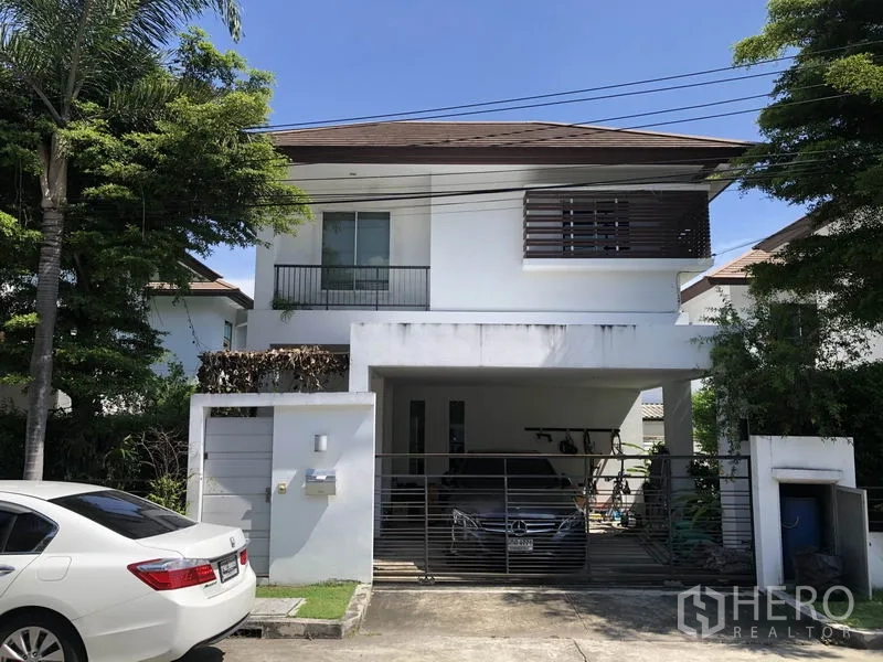 Detached House for rent or sale in Saphan Sung, Bangkok - Two-storey white detached house with gated carport and mature trees in Saphan Sung, Bangkok.