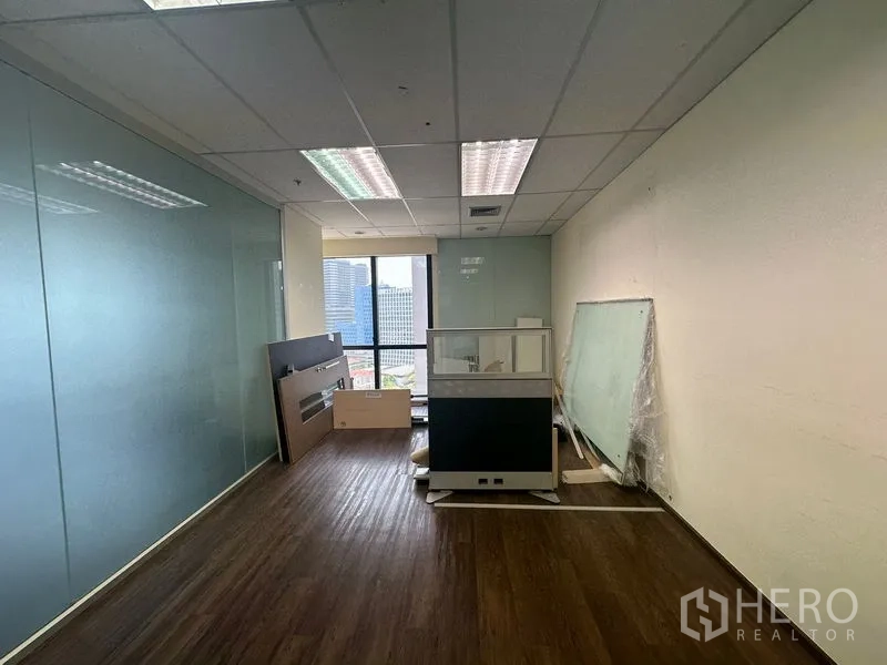 Office Space for rent in Bang Rak, Bangkok - Small office room with city-view window and stored furniture.