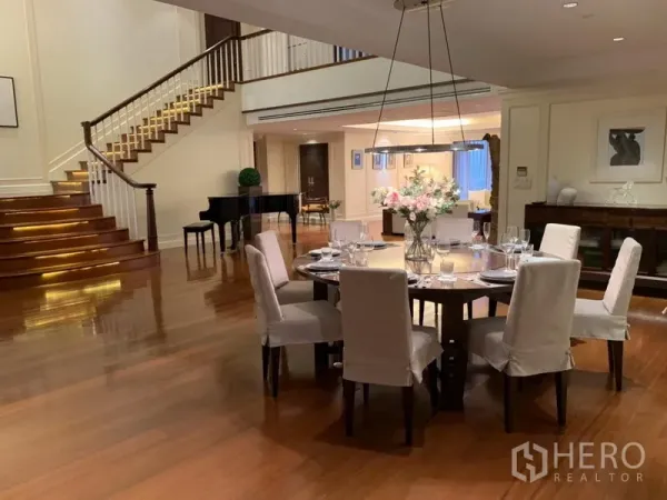 公寓 出租或出售在Watthana, Bangkok - 优雅餐厅，八人圆桌，旁有楼梯与钢琴装饰。