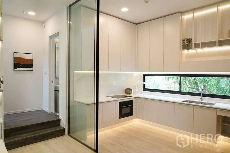 Detached House for rent in Saphan Sung, Bangkok - Second kitchen with L-shaped counters, under-cabinet lighting and sliding glass partition.