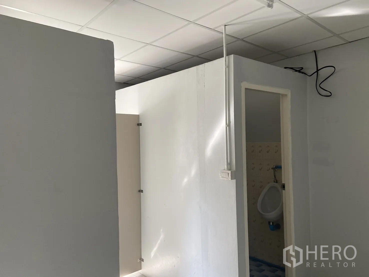 Shophouse for rent in Bang Na, Bangkok - Tiled restroom zone with cubicles and a urinal under a suspended ceiling.