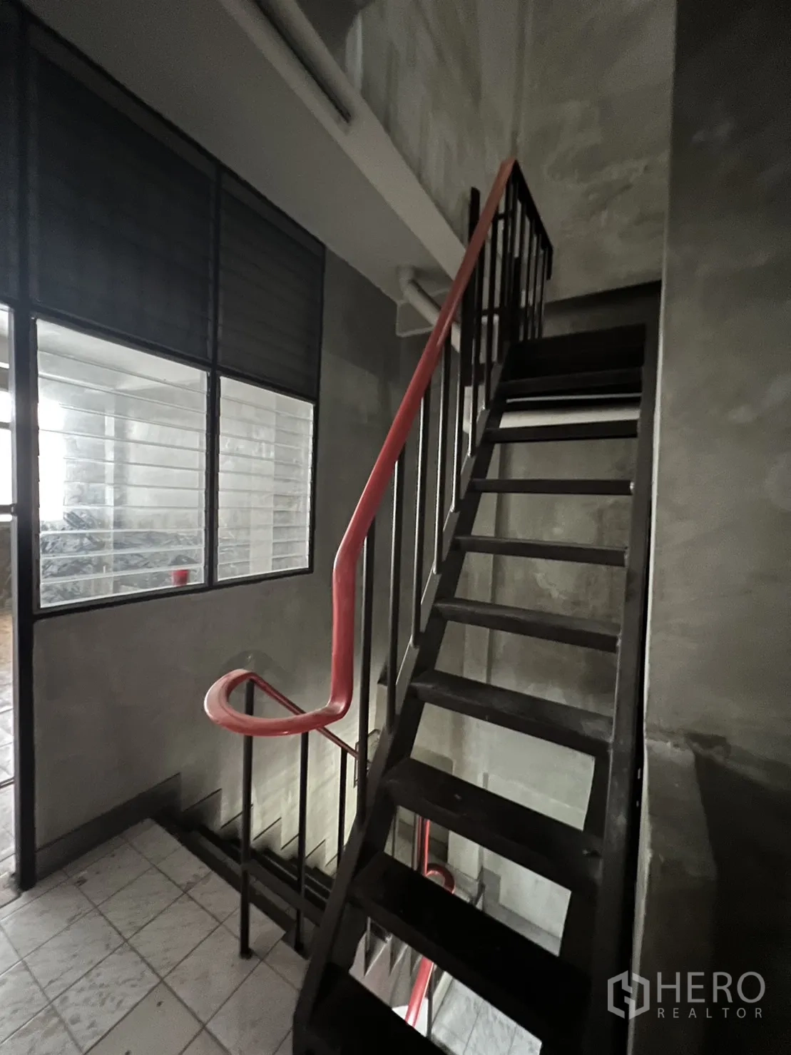 Shophouse for rent in Watthana, Bangkok - Metal staircase with red handrail beside louvered windows.