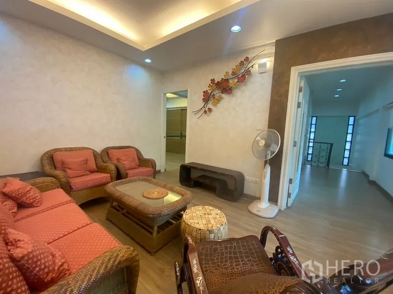 独立式住宅 出售在Khlong Toei, Bangkok - 家庭起居室，藤编沙发、墙面装饰与暖色顶灯。