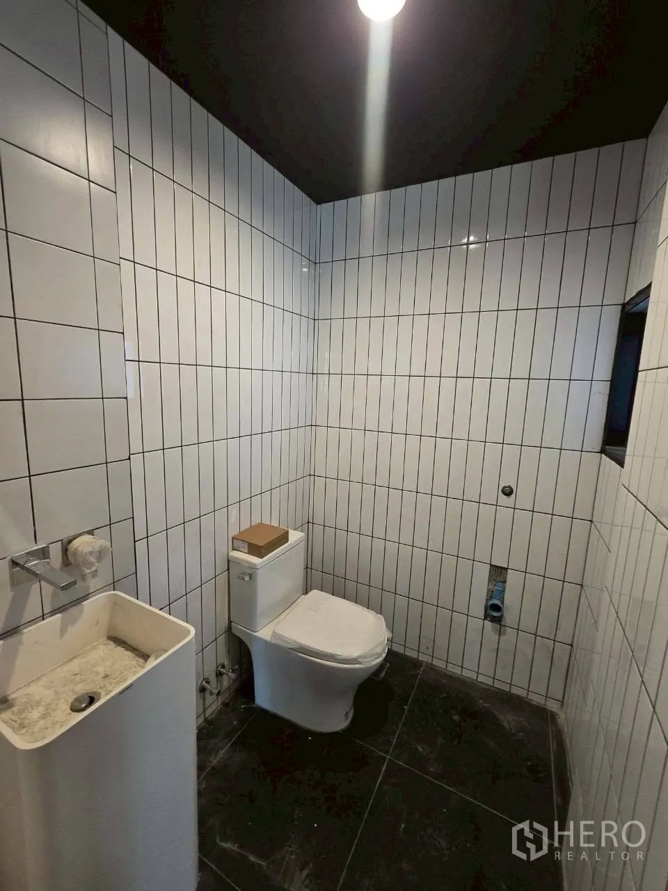 独栋房屋 for rent in Phra Khanong, Bangkok - 浴室采用竖向白色瓷砖，配坐便器与立式洗手盆，深色天花。