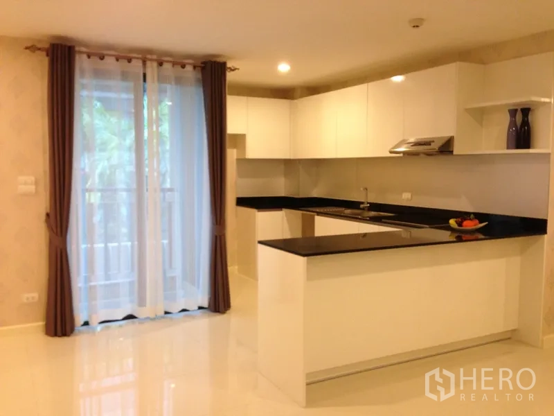 公寓 出租或出售在Watthana, Bangkok - 开放式白色厨房，黑色石材台面，推拉落地门通向阳台，曼谷公寓。
