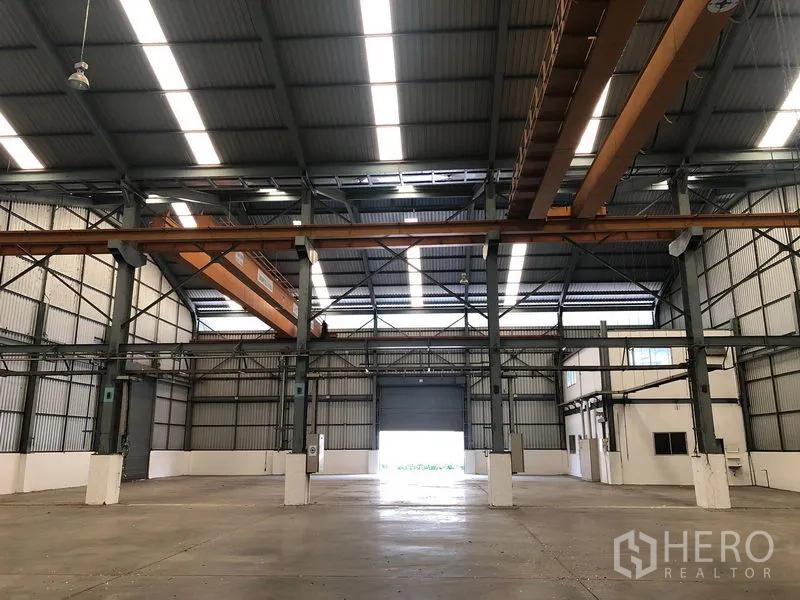 Factory for rent in Khlong Luang, Pathum Thani - Open production hall with high ceiling, skylights and dual roller doors.