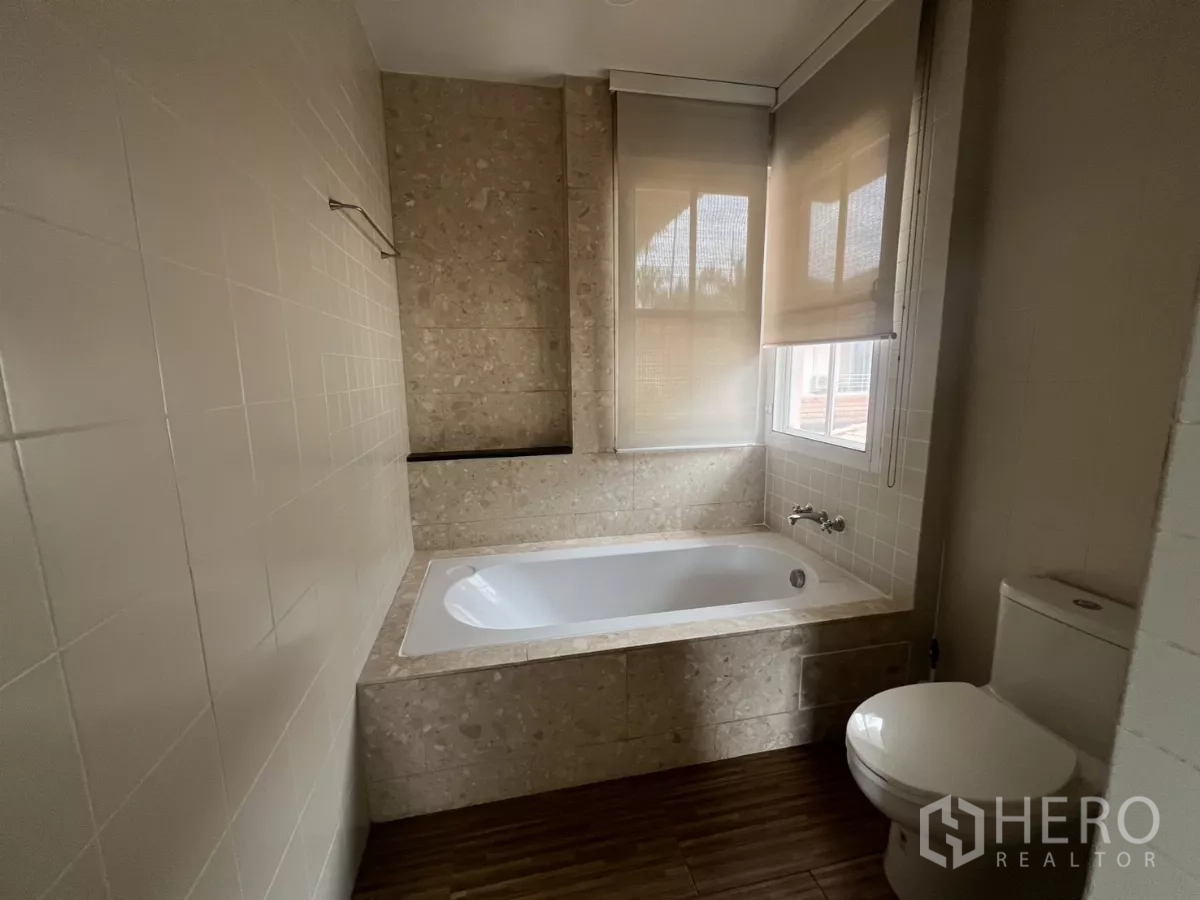 Detached House for rent in Wang Thonglang, Bangkok - Bathroom with built-in bathtub, tiled walls and window shades.