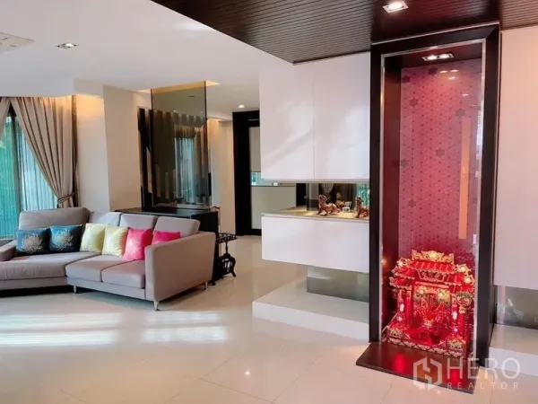 独立式住宅 出租或出售在Prawet, Bangkok - 明亮开放式客厅，转角沙发、亮面瓷砖地面与内置展示柜。