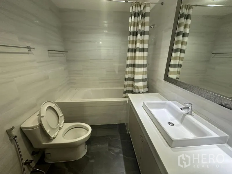 คอนโด ให้เช่าในWatthana, Bangkok - ห้องน้ำโมเดิร์นพร้อมอ่างอาบน้ำ เคาน์เตอร์ยาว และผ้าม่านลายทาง ในคอนโดใกล้ BTS พร้อมพงษ์