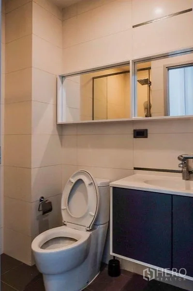 Condominium for rent in Khlong Toei, Bangkok - Second bathroom with mirror cabinet, toilet and under-sink storage.