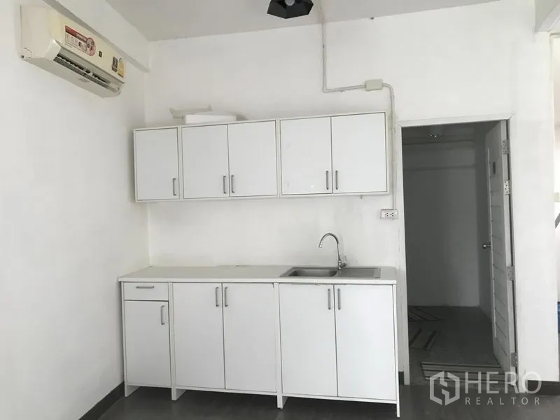 店屋 出租在Watthana, Bangkok - 整面茶水间柜体与水槽，上方有空调，旁边是湿区门