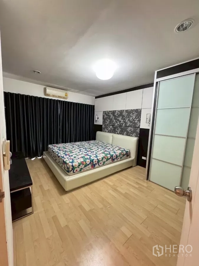 Townhouse for rent in Suan Luang, Bangkok - Second bedroom view toward dark drapes and media console.