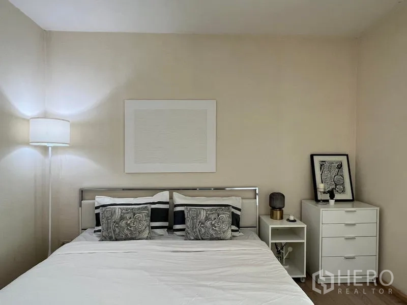 Condominium for rent in Khlong Toei, Bangkok - Bedroom with double bed, floor lamp and chest of drawers.
